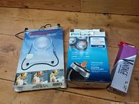 Three packaged items laid out: BabyBjorn carrier, Philips shaver, Vantage box