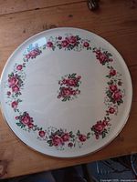 Top view of round cake plate showing floral pattern, metallic rim, no chips visible