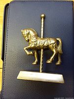 front view of brass carousel horse on pole with base