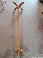 Full view of wooden children’s coat rack laid horizontally showing base and top peg area