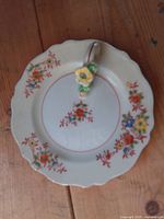 Top view of scalloped porcelain cookie plate with floral decoration and central flower handle
