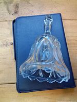 Side view of clear crystal bell on dark base