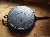 Underside of cast iron frying pan showing "VICTORIA" embossing, helper handle and main handle visible