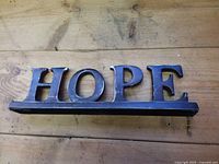 Front view of metal HOPE sign showing full word and base