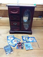 Jewelry chest, five Pokémon cards and three sealed toy packs arranged on wooden surface
