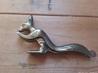 Full side view of solid brass squirrel-shaped nutcracker showing lever tail and body details