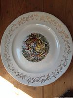 Front view of plate showing pastoral scene and gold vine border