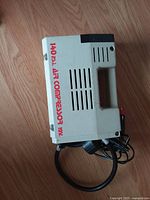 Side view of beige 12V 140 PSI portable air compressor with handle, power cord and air hose visible