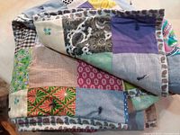 Folded handmade patchwork quilt showing varied fabric squares and binding