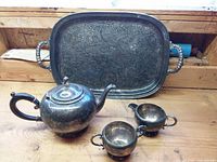 All four silver-plated items grouped: tray, teapot, creamer, sugar bowl