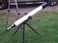 White Tasco refractor on tripod set on lawn