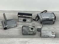 Group shot of five cameras laid out on wood surface