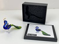 Peacock figurine beside open box and card