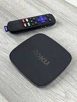 Roku streaming device and remote shown together on wood surface