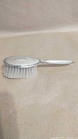 Side profile of sterling silver-handled hairbrush showing bristles and handle.