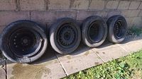 Set of four tires on rims leaning against wall
