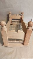 Overall view of doll cradle from foot showing spindle posts and rope base