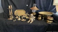 All fifteen brass decor items arranged on dark backdrop
