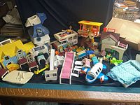 Overview of mixed Fisher-Price Little People playsets, furniture, airplane and accessories spread on table