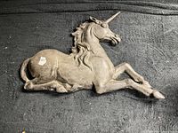 Full view of cast iron unicorn plaque against black background