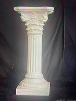 Full view of white ceramic Corinthian pedestal showing capital, fluted shaft, square base