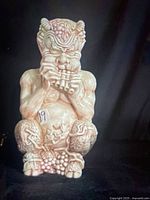 Front view of ivory-cream marbled ceramic satyr/faun figurine in seated pose playing pan flute