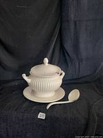 Four-piece white/ivory fluted ceramic soup tureen, lid, underplate and ladle displayed together