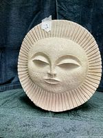 front view of beige ceramic sun face plaque showing overall design and condition