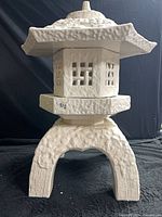 Front view of glossy white ceramic pagoda lantern on black backdrop