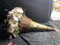 Overall view of metal cornucopia planter with artificial flowers