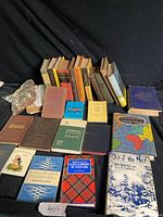 Single image showing approximately 27 mixed vintage books laid out on black cloth