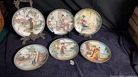 Front view of all six decorated plates set on fabric backdrop