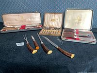 Overview of three boxed antler-handled cutlery sets with loose pieces displayed
