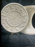 Round ceramic tabletop showing zodiac relief beside matching pedestal base