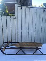 Full side view of sled showing wood deck, metal frame, runners, and handle