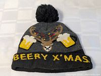 Full view of front of hat showing pom-pom, graphic and text