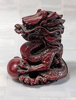 Front view of red resin dragon holding pearl