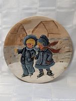 Full view of round painted plate showing skating children and village background
