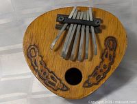 Front view showing full instrument including seven tines, sound hole, carved designs