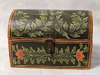 Front view of domed wooden box showing painted leaf and flower design