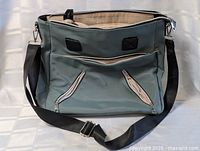 Front view of sage-green leather purse with strap and pockets