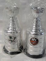 Two sealed silver Stanley Cup-shaped cups side by side showing both team logos
