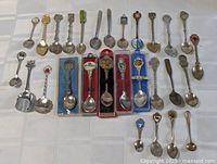 Full group of 29 souvenir teaspoons displayed on table