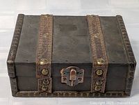 Closed view of wooden jewelry box showing straps and latch