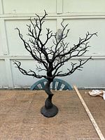 Full view of black plastic jewelry display tree on table with ruler for scale