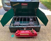 Stove open showing burners, grate and red fuel tank