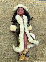Full view of doll in fur coat, hat, boots, tag visible