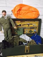 Open footlocker showing figure, clothing, boots, raft and printed interior