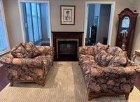 Front view of sofa and loveseat showing floral upholstery and wood feet
