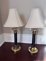 Front view showing both matching black speckled column table lamps with brass-tone bases and white shades